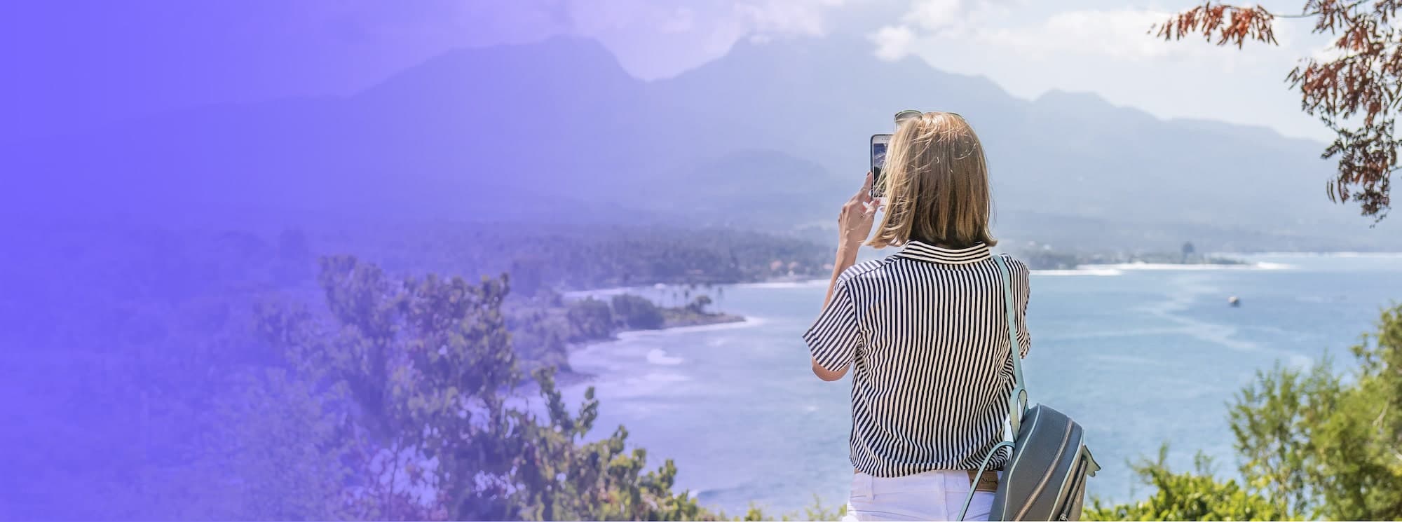 Persona fotografiando un paisaje de costa con su celular